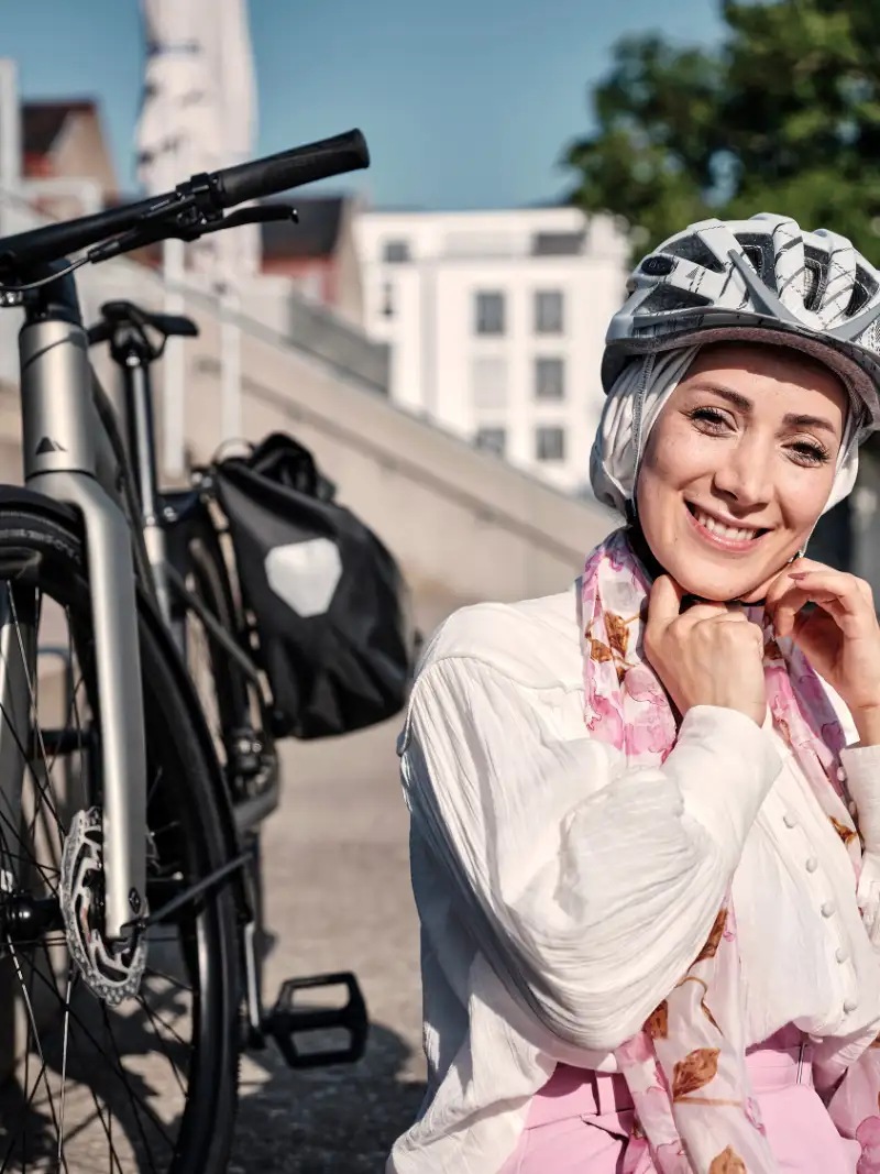 Frau sitzt mit Helm und Fahrrad in der Sonne