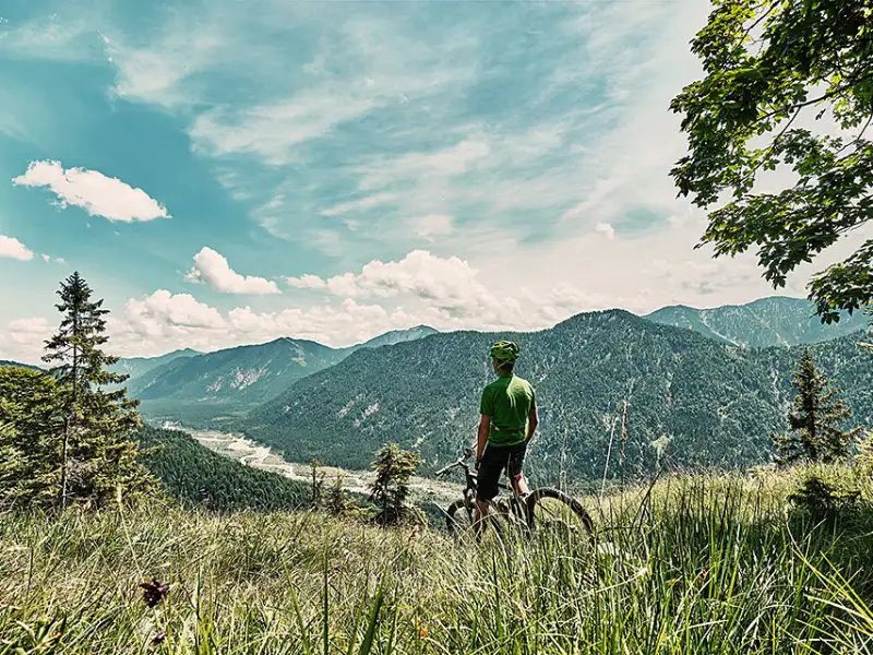 Mountainbiker auf Bergwiese mit Aussicht ins Tal