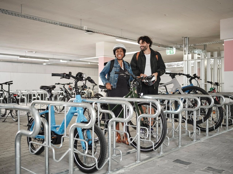 Zwei JobRadler:innen steigen aufs Fahrrad im Fahrradkeller. Zwei JobRadler:innen steigen aufs Fahrrad im Fahrradkeller.