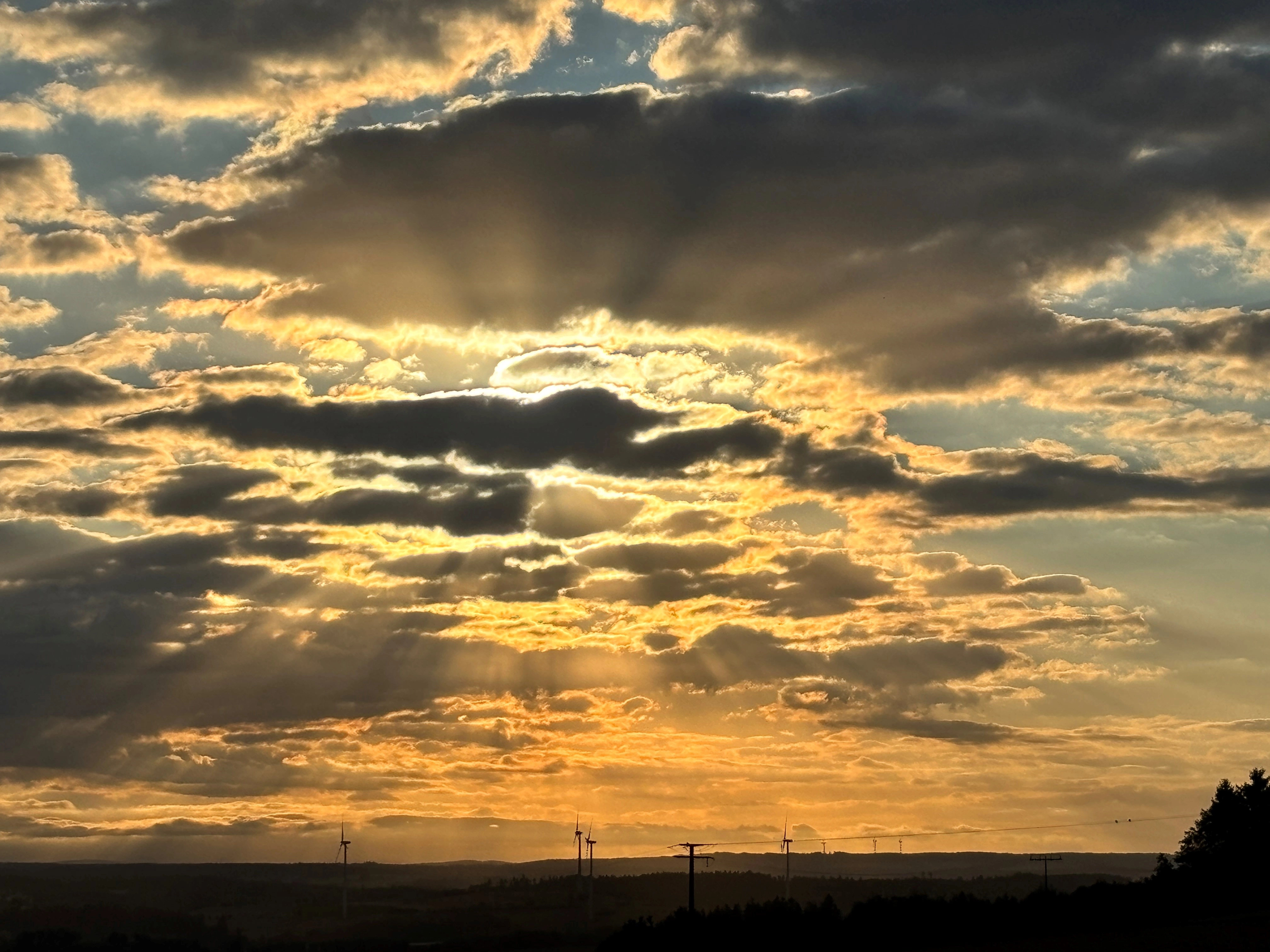 Ein spektakulärer Sonnenuntergang mit Wolken und Windkraftanlagen.