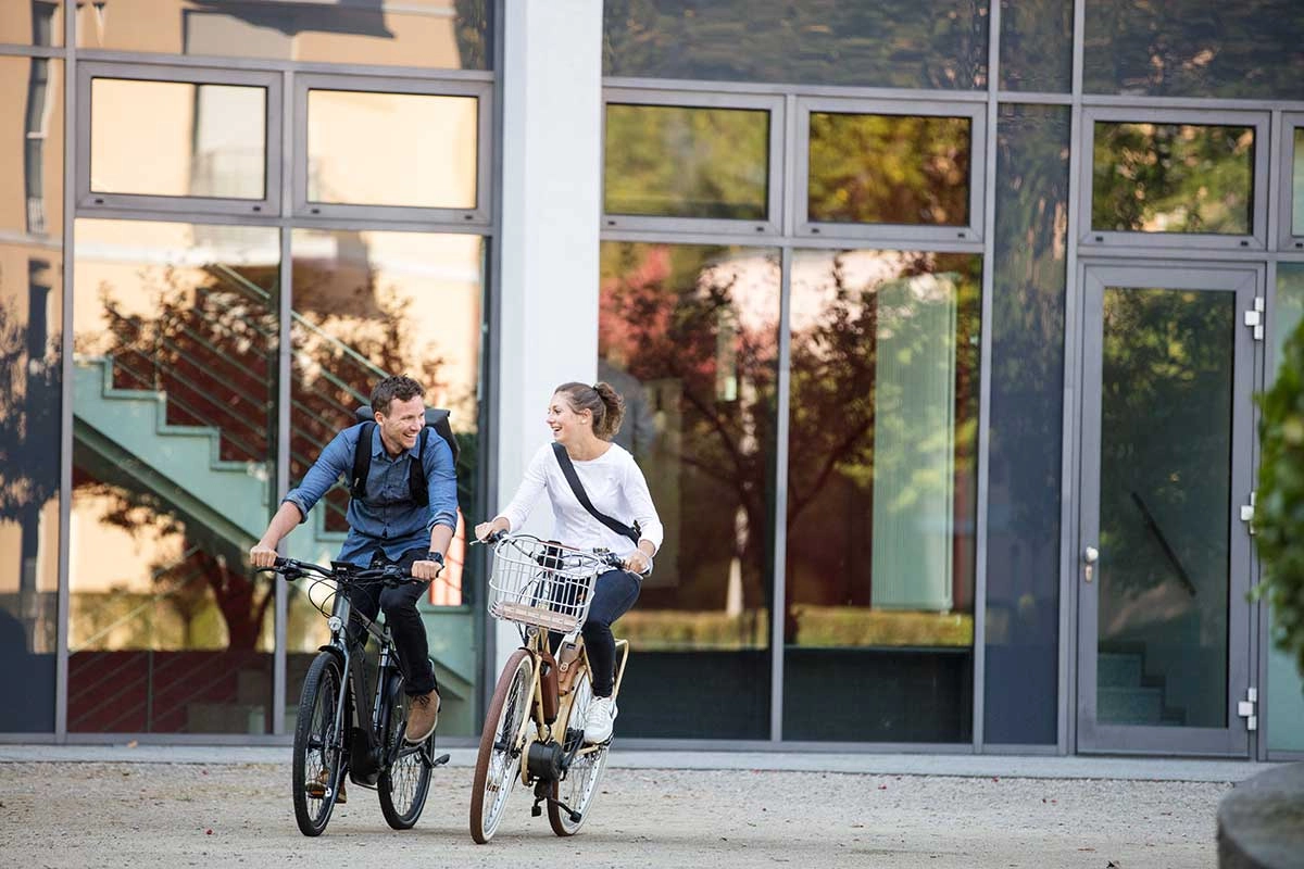 Zwei Radfahrer:innen fahren zufrieden in den Feierabend